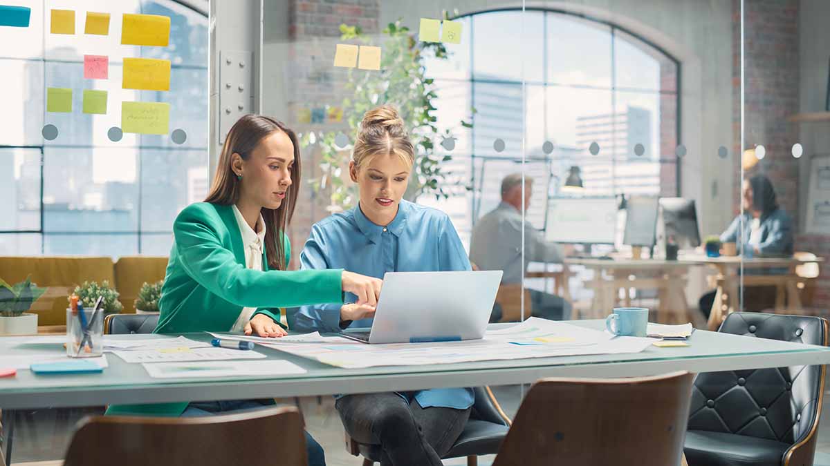 Two young lady colleagues working on a laptop together.