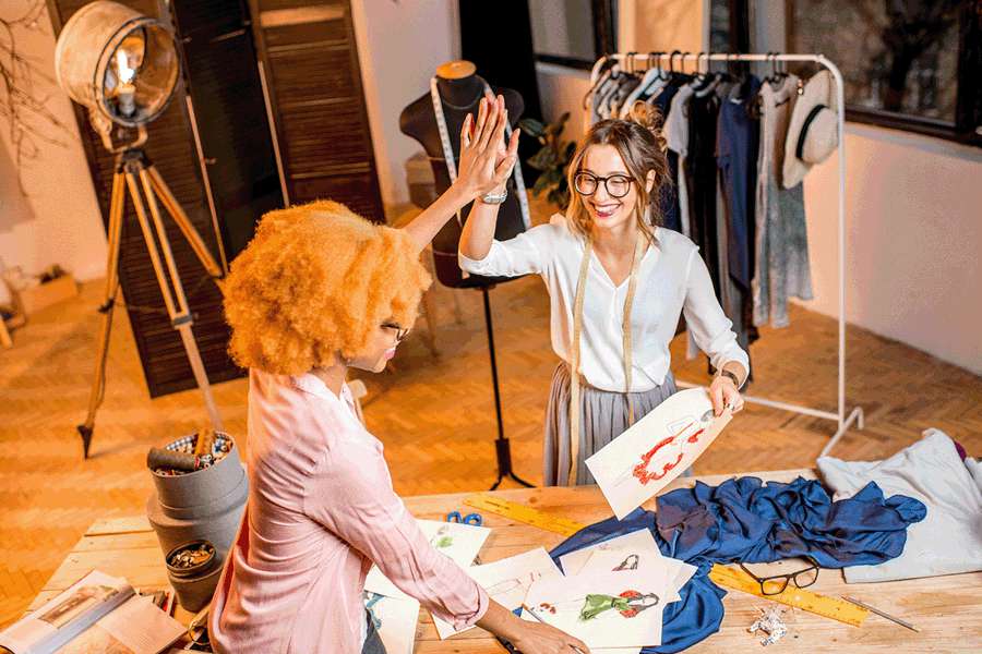 Two young business ladies are giving each other high fives